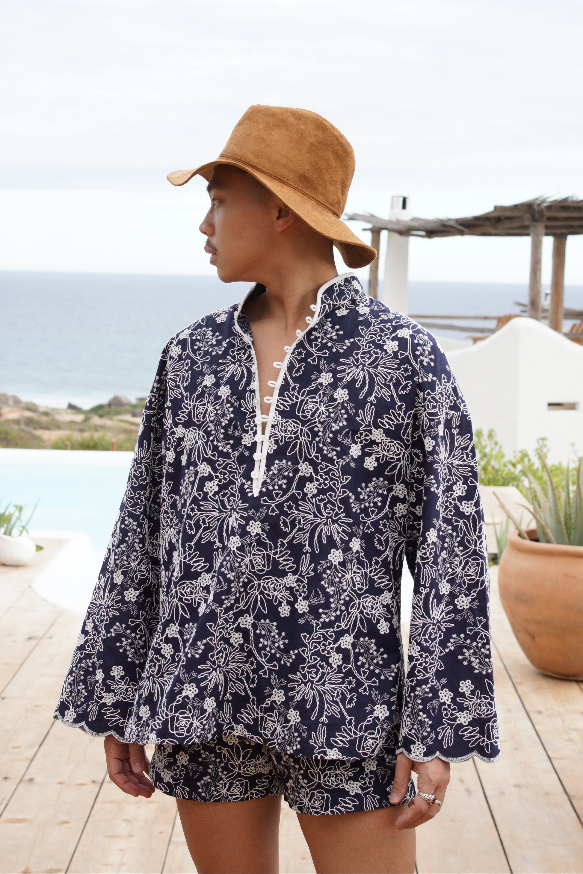 Person wearing an embroidered set and hat by a poolside